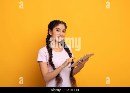 Giovane donna indiana sicura che tiene e usa il tablet Foto Stock