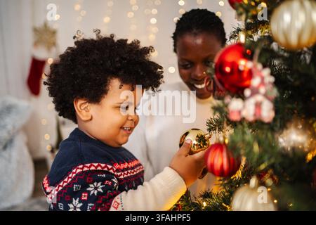 Madre e figlio decorano insieme l'albero di Natale Foto Stock