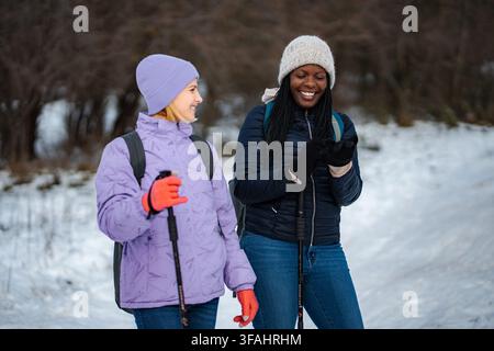 Diverse amiche che si divertono a fare escursioni invernali insieme ridendo Foto Stock