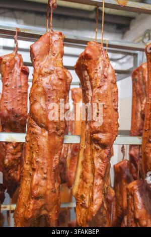 Pancia di maiale affumicata e condita appesa nella affumicatore. Foto Stock
