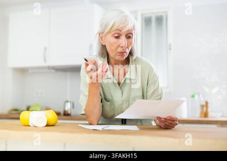 Donna che usa il telefono e lavora con i documenti Foto Stock