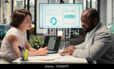 Candidato al lavoro maschile che firma il nuovo contratto di lavoro dopo essere stato accettato nell'organizzazione, professionista delle risorse umane che garantisce il processo di inserimento con documenti di lavoro e termini legali. Foto Stock