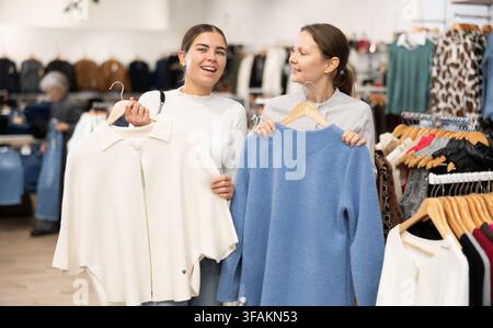 Due donne che scelgono un maglione comodo nel negozio di abbigliamento Foto Stock