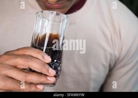 Persona che tiene un bicchiere di bibite analcoliche al chiuso Foto Stock