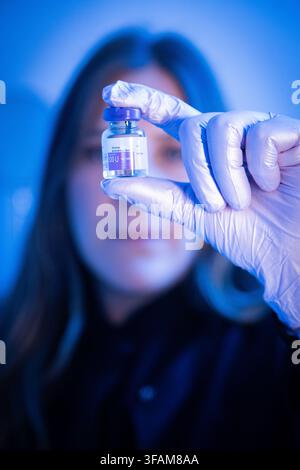 Infermiera mascherata che presenta una fiala di tossina botulinica alla telecamera Foto Stock