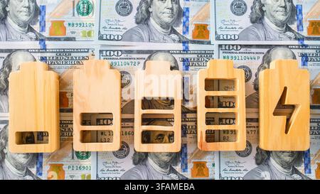 Concetto di costo energetico e bolletta elettrica con icone in legno del livello di carica della batteria su banconote da cento dollari per le spese di consumo energetico, rinnovabile Foto Stock