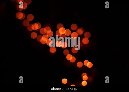 Composizione astratta con sfere luminose rosse e arancioni sparse su uno sfondo nero scuro, creando un'atmosfera misteriosa e artistica Foto Stock