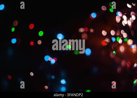 Sfondo astratto con luci bokeh colorate che presentano forme circolari luminose in varie colori vivaci sparse su una composizione scura. Foto Stock
