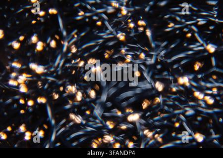 Fotografia astratta a lunga esposizione che cattura una fitta rete di luci dorate luccicanti con sfocatura del movimento che crea dinamiche strisce di luce a vortice Foto Stock