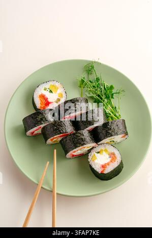 Rulli di sushi maki freschi serviti su un piatto verde Foto Stock