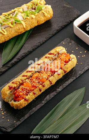 Rotoli di sushi fritti caldi serviti su ardesie nere Foto Stock