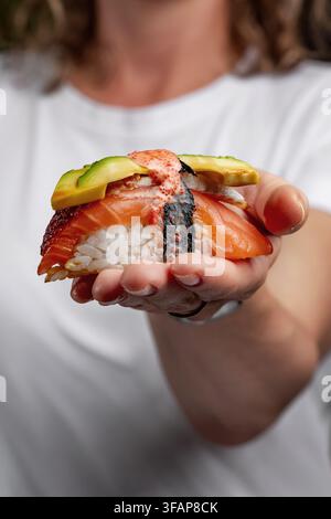 Donna che tiene un grosso pezzo di sushi di design Foto Stock