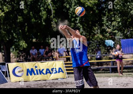 Atleta maschio lancia la palla giocando a beach volley Foto Stock