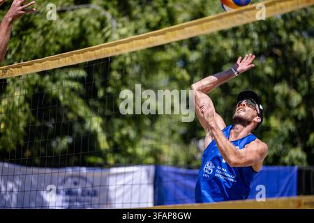 Giocatore di beach volley che spacca la palla sopra la rete Foto Stock
