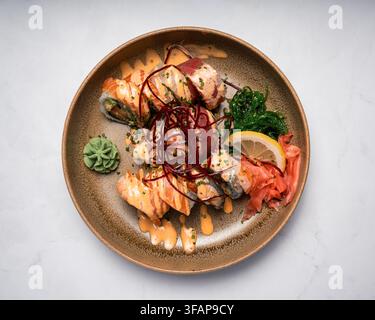 Roli di sushi splendidamente impiattati con salsa e wasabi Foto Stock