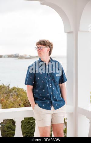 Giovane uomo guarda fuori da un balcone bianco Foto Stock