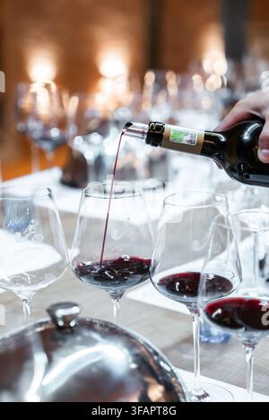 Vino rosso versato nei bicchieri durante una sessione di degustazione Foto Stock