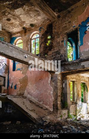 Interno in rovina con pavimenti collassati e finestre ad arco all'interno dell'ex Palazzo dei Giovani Pionieri a Chiatura, Georgia. Foto Stock