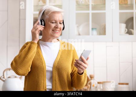 Ritratto di una donna anziana felice che ascolta la musica sullo smartphone Foto Stock