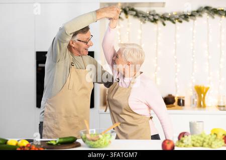 Coppia matura che balla in cucina, divertiti a cucinare a Natale Foto Stock
