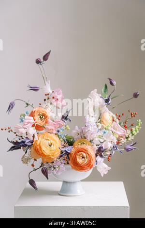 Vivace composizione floreale di ranuncoli in vaso bianco Foto Stock