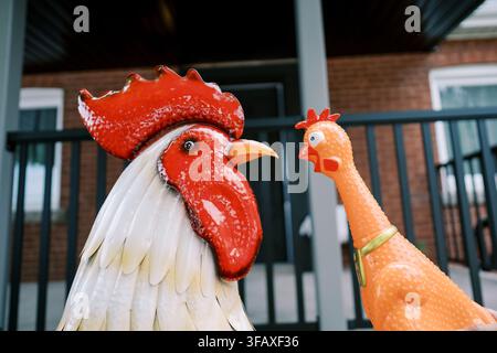 Gallina di ceramica e gallina di gomma si fronteggiano sul portico Foto Stock