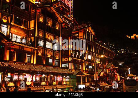 Luce dorate calde illuminano l'architettura tradizionale delle case su palafitte di Hongyadong (Grotta di Hongya) di notte a Chongqing, nel sud-ovest della Cina. Foto Stock