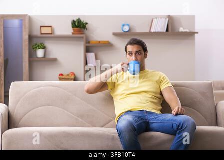 Giovane studente beve caffè a casa Foto Stock