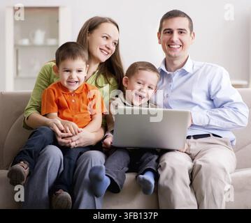 La giovane famiglia sta navigando su Internet e guardando foto Foto Stock