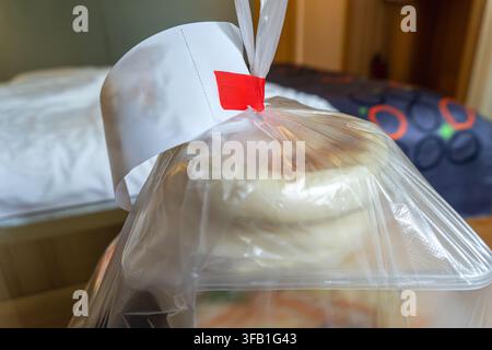 Busta di plastica con cibo sul letto nella camera d'albergo. Foto Stock