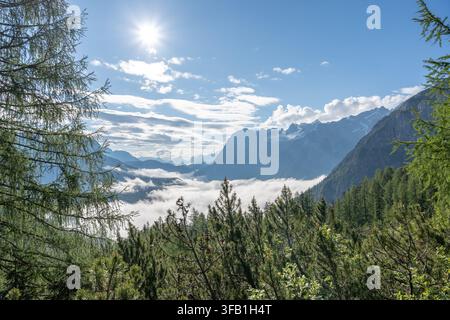 Sole che splende sulle montagne Dolomiti con nuvole nella valle Foto Stock