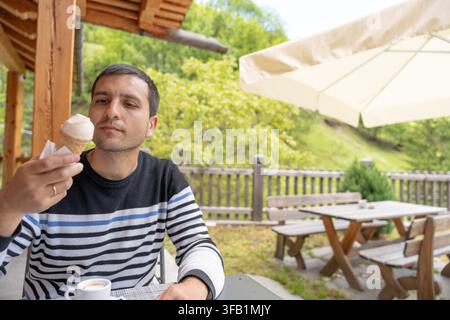 Giovane uomo che assapora un gelato all'aperto in vacanza Foto Stock