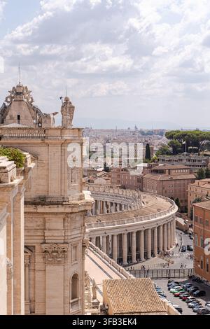 Vista elevata dalla Basilica di San Pietro nella Città del Vaticano, che mostra il maestoso colonnato di Bernini, i tetti storici di Roma, i monumenti e i visitatori sottostanti Foto Stock