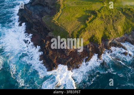 Vista aerea delle onde che si infrangono contro la costa rocciosa e frastagliata di Kendalls Beach, Kiama, Nuovo Galles del Sud, Australia, con scogliere verdi e Foto Stock
