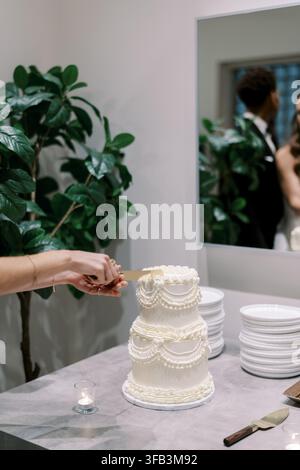 Elegante torta nuziale bianca che viene tagliata Foto Stock