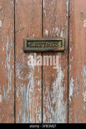 Vecchia fessura per la posta su una porta di legno dipinta che si stacca. Francia Foto Stock