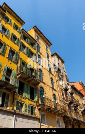 Facciate gialle storiche con persiane in legno verdi in Piazza delle Erbe nel centro città di Verona, Italia. Foto Stock