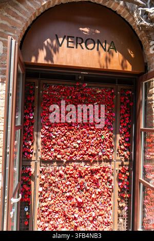 Muro di lucchetti rossi dell’amore a Verona con nomi romantici e date scritte sul lucchetto. Verona, Italia - 25 giugno 2026. Foto Stock