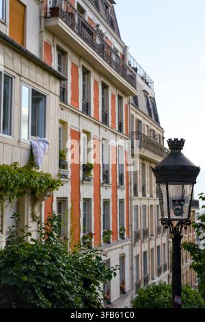 Lampada da strada in ferro nero ornata davanti a una facciata di appartamento color crema e terracotta a Montmartre, Parigi, Francia. Foto Stock