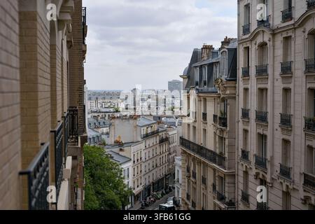 Vista tra edifici residenziali ornati attraverso una strada stretta, tetti a mansarda e camini a Montmartre, Parigi, Francia. Foto Stock