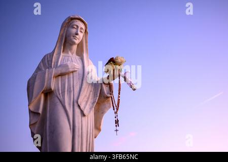 Statua della Beata Vergine Maria al tramonto sul Monte Podbrdo, la collina delle apparizioni che sovrasta il villaggio di Medjugorje, Bosnia-Erzegovina. Foto Stock
