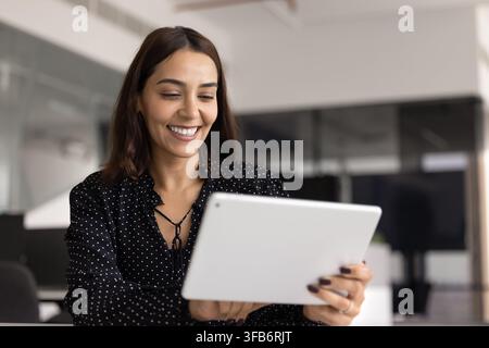Donna felice che utilizza un tablet digitale in ufficio Foto Stock