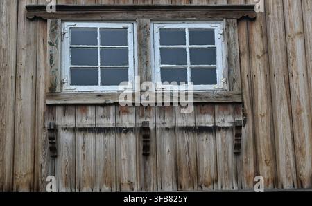 Finestra di fienile in legno stagionato con vernice bianca scrostata sull'esterno rustico della fattoria Foto Stock