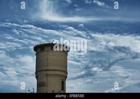 Antica torre d'acqua in mattoni contro un drammatico cielo blu Foto Stock