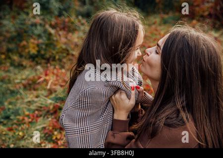 Madre e figlia condividono un momento gioioso in un paesaggio autunnale vivace. Foto Stock