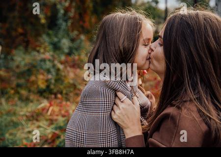 Madre e figlia condividono un momento d'amore all'aperto nella stagione autunnale. Foto Stock