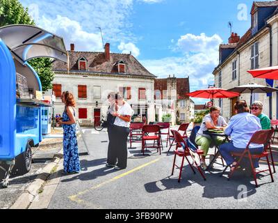 Carrello mobile per caffè e snack parcheggiato nella piazza del paese con persone sedute su sedie e tavoli - Beaulieu-lès-Loches, Indre-et-Loire (37), Francia. Foto Stock