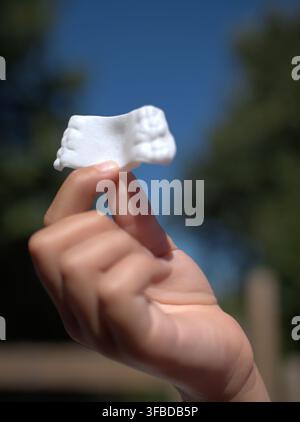 Mano che tiene un retainere dentale bianco contro il cielo Foto Stock