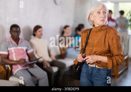 Donna matura in piedi nell'area della reception Foto Stock