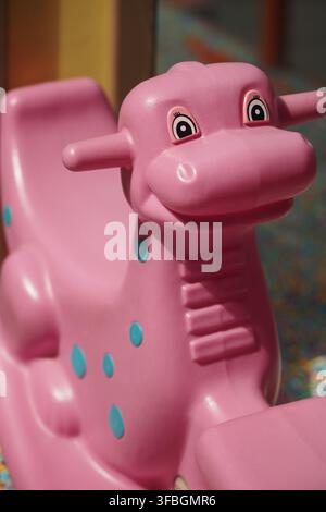 Dinosauro giocattolo colorato in un'area di gioco per bambini Foto Stock